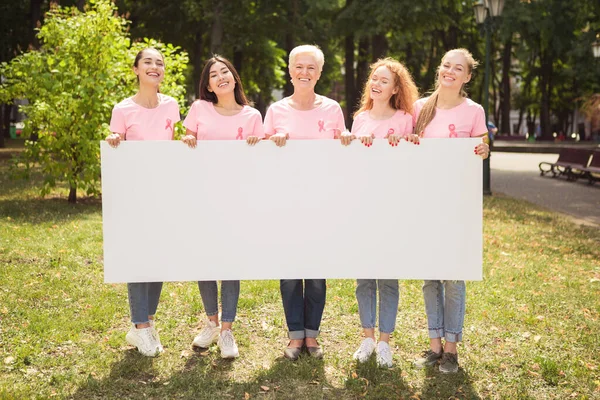 Mujeres con oncología símbolo cinta celebración cartel de pie en el parque — Foto de Stock