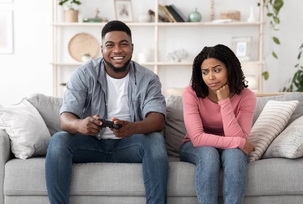 Βαρετό ραντεβού. Ενθουσιασμένος μαύρος που παίζει βιντεοπαιχνίδια και αγνοεί την κοπέλα του δίπλα του. — Φωτογραφία Αρχείου
