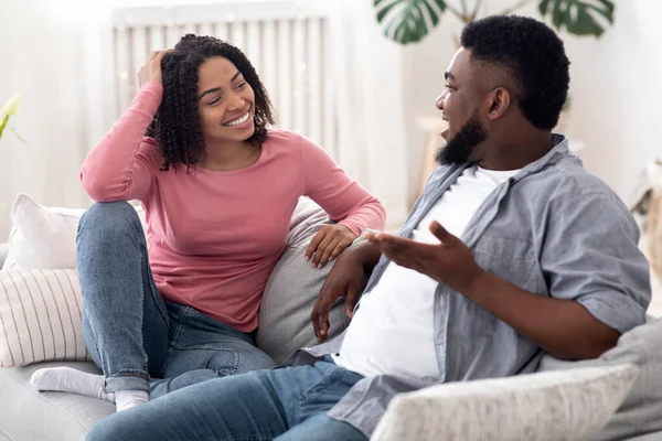Ласковая афро-пара проводит время вместе дома, болтая и смеясь — стоковое фото