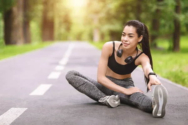 Joven asiática chica estiramiento piernas antes de trotar al aire libre, calentamiento para el entrenamiento — Foto de Stock