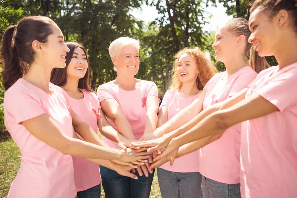 Női önkéntesek, akik mellrákos betegeket támogatnak kéz a kézben a parkban — Stock Fotó