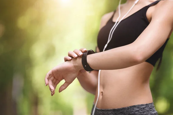 Onherkenbare atleet vrouw controleren fitness armband indicatoren tijdens het joggen buiten, close-up — Stockfoto