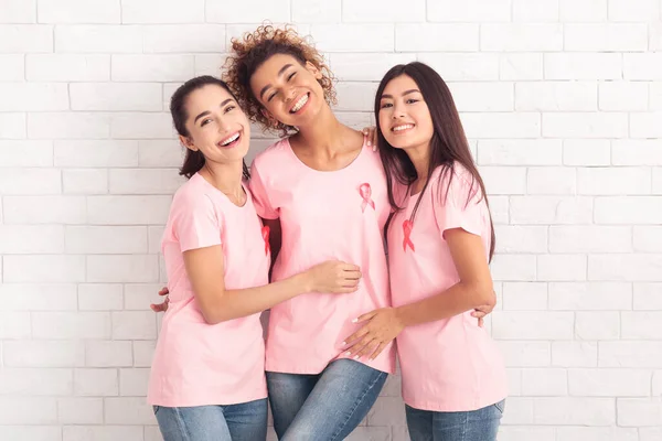 Tre diverse ragazze volontarie del cancro al seno che abbracciano su sfondo bianco — Foto Stock