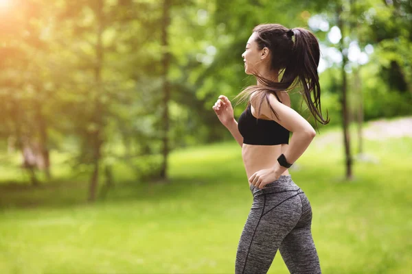 Активный образ жизни. Мотивированная азиатская девушка бегает трусцой в парке, носит стильную спортивную одежду — стоковое фото