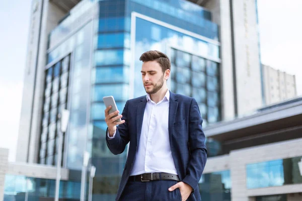 Magabiztos fiatal vállalkozó ellenőrzi a mobiltelefon üzenetek a város utcájában — Stock Fotó