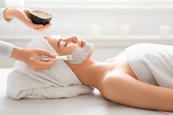 Terapeuta de spa aplicando máscara de barro en la cara de mujer —  Fotos de Stock