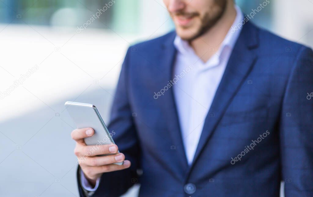 Closeup view of man in business suit using his smartphone in urban area