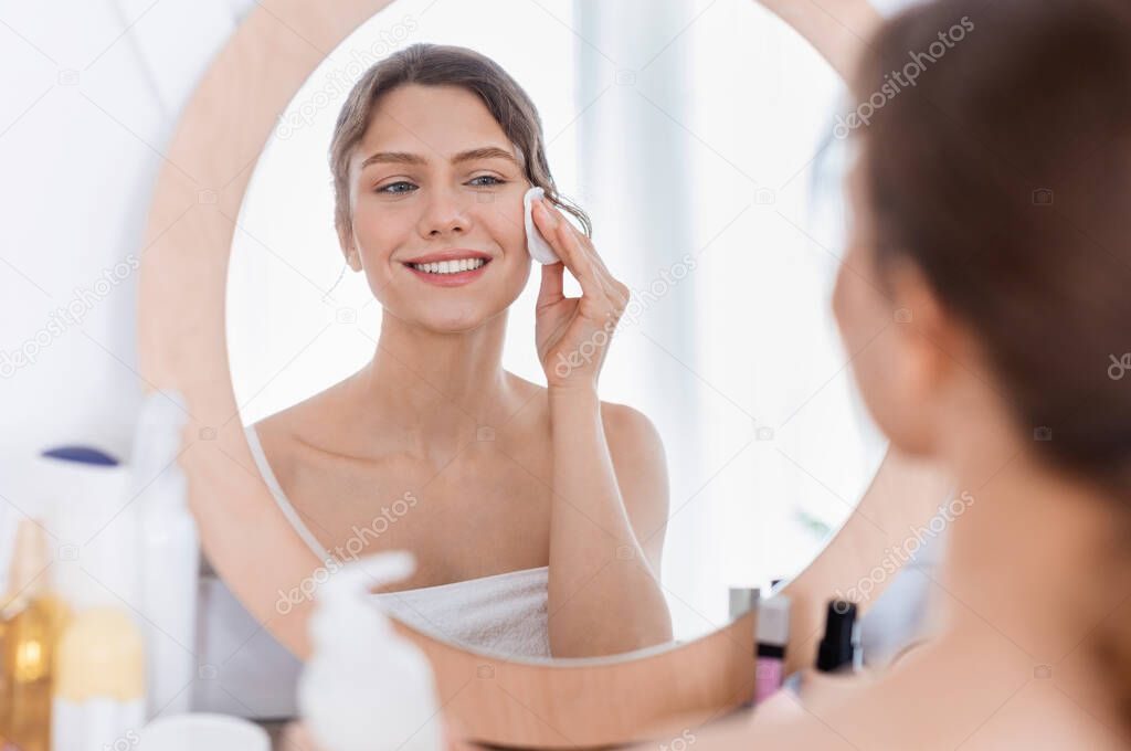 Fresh looking girl using cotton pad, cleamsing morning procedures