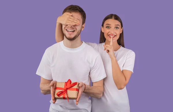 Ragazza coprendo i suoi occhi fidanzato e dandogli presente — Foto Stock