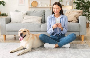 Cep telefonu kullanan köpeğiyle birlikte genç bir kadının portresi
