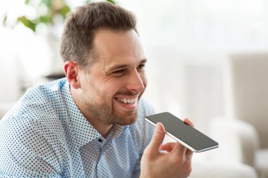 Yetişkin adam akıllı telefonda ses asistanı kullanıyor