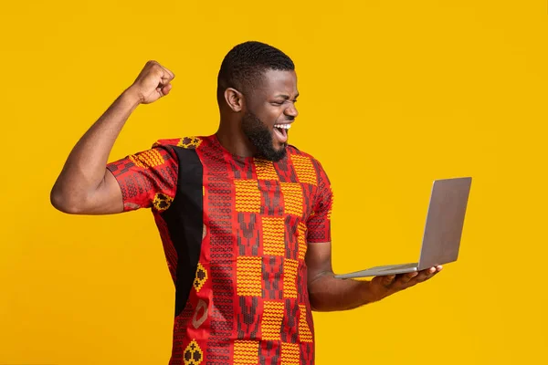 Емоційний африканський хлопець з ноутбуком виражає щастя — стокове фото