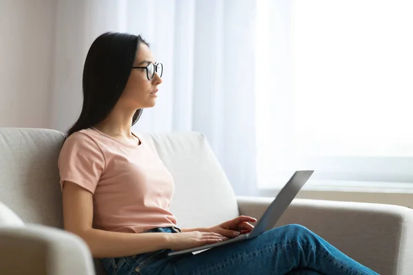 Studente ragazza utilizzando computer portatile pensare seduto sul divano a casa — Foto Stock