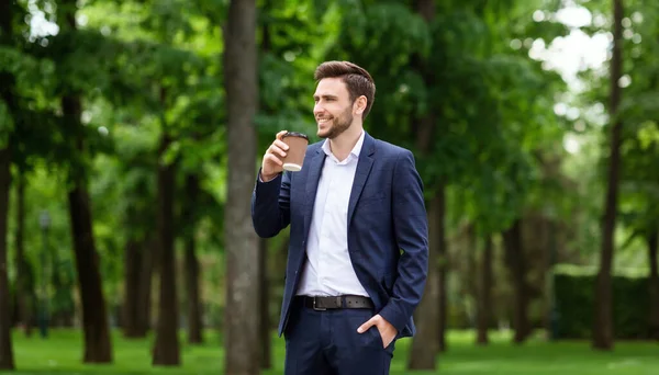 CEO confiante com café de takeout desfrutando de sua caminhada matinal no parque urbano — Fotografia de Stock