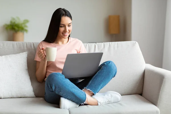 Donna rilassante con computer portatile guardando film godendo caffè seduto al coperto — Foto Stock