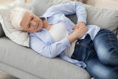 Acute Pancreatitis. Sad elderly woman holding her abdomen, suffering from stomach ache clipart