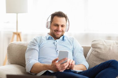 Kanepede oturmuş müzik dinleyen mutlu adam.
