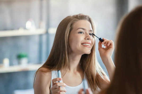 Belleza y maquillaje. Dulce dama aplicando rímel en sus pestañas cerca del espejo en el baño —  Fotos de Stock