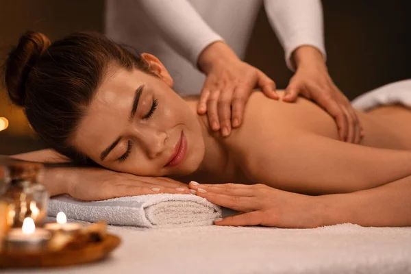 Chica alegre recibiendo masaje corporal con aromaterapia en el spa —  Fotos de Stock