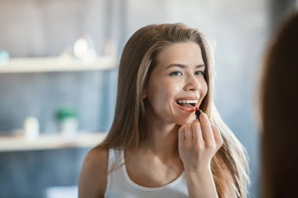 Schöne Millennial Mädchen Anwendung Lippenstift in der Nähe Spiegel im Badezimmer — Stockfoto