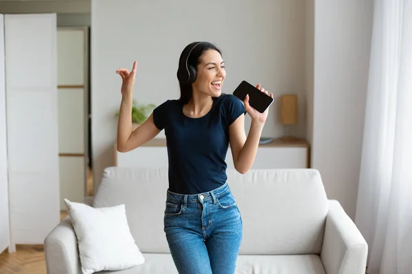 Donna che canta Ascoltare musica che tiene il telefono come il microfono a casa — Foto Stock