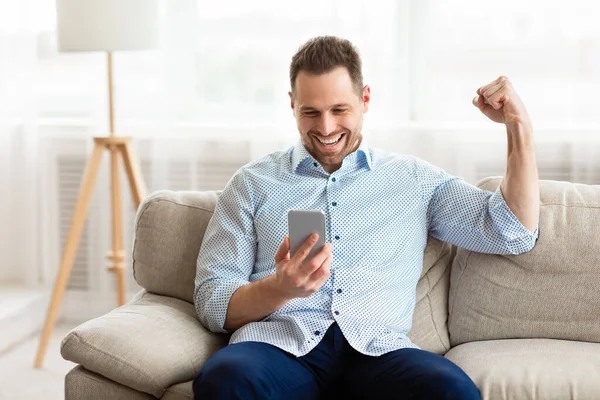 Excited adult man feeling ecstatic holding phone — Stock Photo, Image