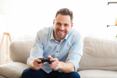 Kanepede oturan adam online video oyunları oynuyor.