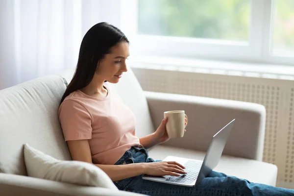 Donna che utilizza il computer portatile rilassante con tazza di caffè a casa — Foto Stock