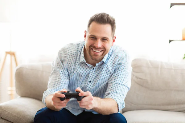 Mann sitzt auf Couch und spielt Videospiele online — Stockfoto