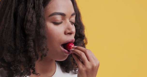 Porträt einer jungen schwarzen Frau, die frische Erdbeeren isst — Stockvideo