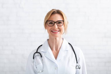 Müşteriyle uzaktan iletişim kurmak. Gülümseyen yetişkin kadın doktor kameraya bakıyor.