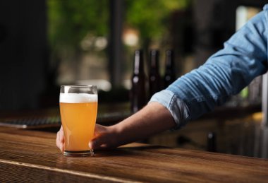 Pub 'da Ekim Festivali. Barmenin eli barın içinde bardakta bira tutuyor.