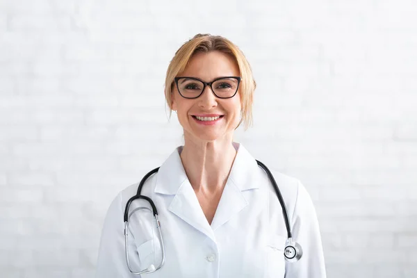 Επικοινωνία με τον πελάτη εξ αποστάσεως. Χαμογελαστή ενήλικη γυναίκα γιατρός κοιτάζοντας την κάμερα — Φωτογραφία Αρχείου