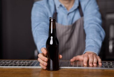 Barda akşam yemeği. Barmen müşterilerine barda bir şişe bira veriyor.