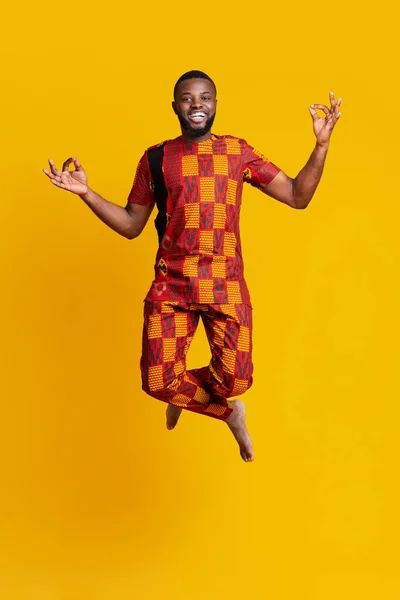 Carefree Africano cara pulando sobre amarelo estúdio fundo — Fotografia de Stock