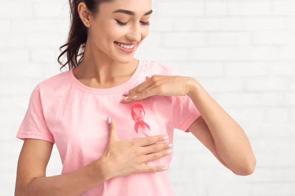 Voluntário de câncer de mama enquadrando fita rosa na camiseta, fundo branco — Fotografia de Stock