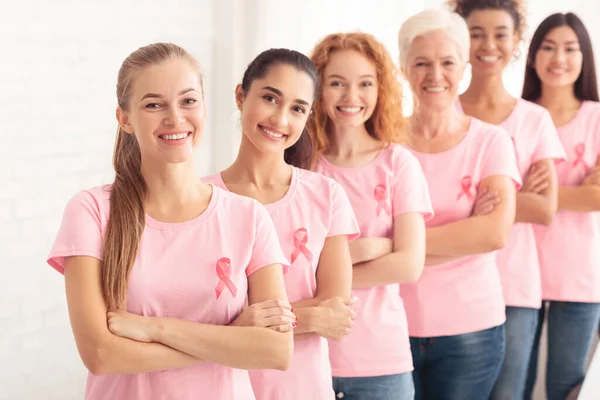 Volontari del cancro al seno in piedi indossando T-shirt con nastro, sfondo bianco — Foto Stock