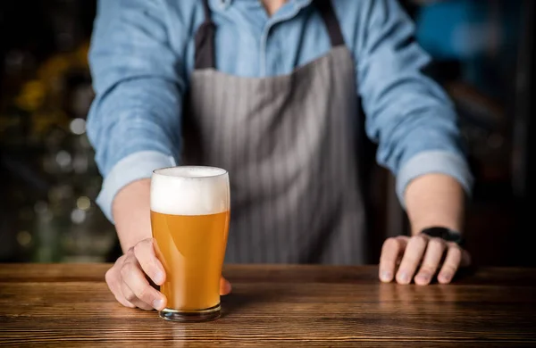 Barda el işi içkisi. Barmen köpüklü bir bardak light bira verir. — Stok fotoğraf