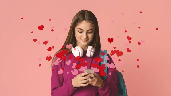 Glimlachend tienermeisje typt op smartphone, harten vliegen uit smartphone — Stockfoto