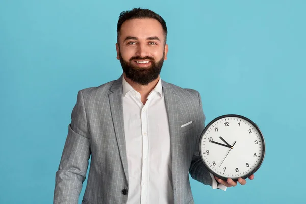 Zeitmanagement und -optimierung. Glücklicher Geschäftsmann mit Analoguhr auf blauem Hintergrund — Stockfoto