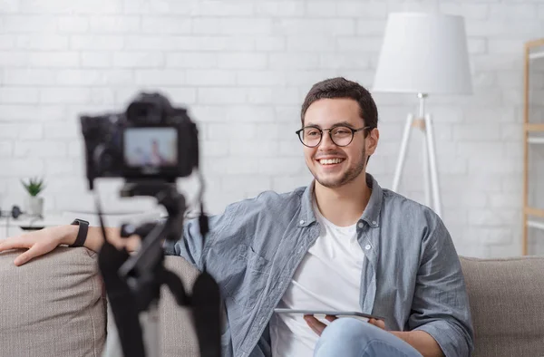 Riprese per il video blog. Ragazzo sorridente tiene tablet in mano e guarda la fotocamera — Foto Stock