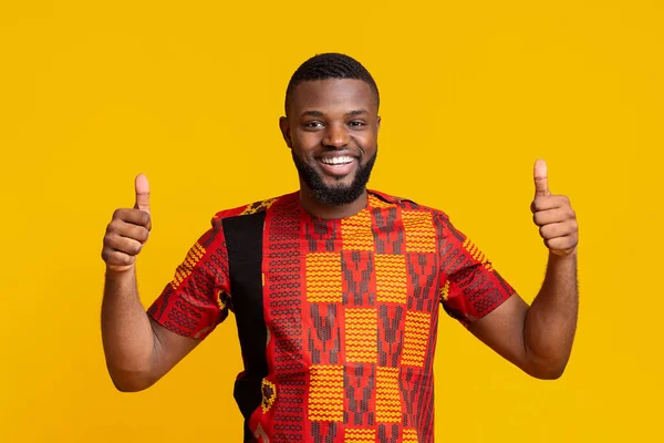 Vidám afrikai srác mutatja hüvelykujját fel sárga háttér — Stock Fotó