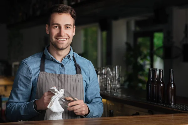 A abrir pub. Barman bonito sorridente em vidro toalhetes avental — Fotografia de Stock