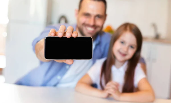 Pai e filha mostrando Smartphone tela em branco sentado na cozinha — Fotografia de Stock