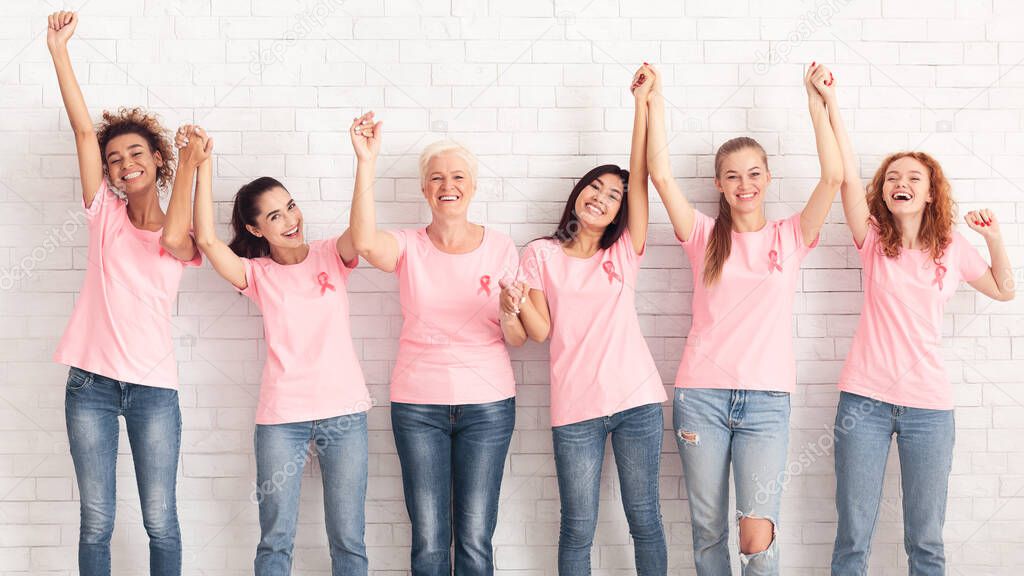 Breast Cancer Support Group Holding Raised Hands Over White Wall