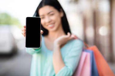 Alışveriş Uygulaması. Alışveriş Torbalı Asyalı Kız Siyah Ekranlı Akıllı Telefon Gösteriyor