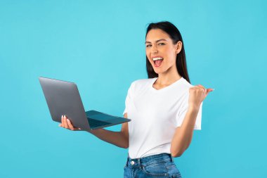 Mutlu bayan çalışan elinde dizüstü bilgisayarla kendinden geçmiş hissediyor.