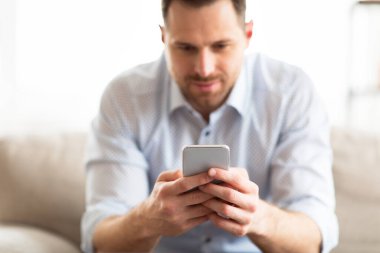 Evde akıllı telefon kullanan yakışıklı bir yetişkin.