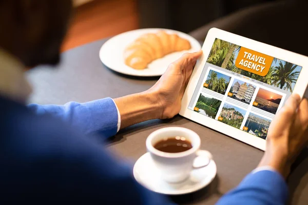 Black Man Using Online Travel Agency Website On Digital Tablet In Cafe