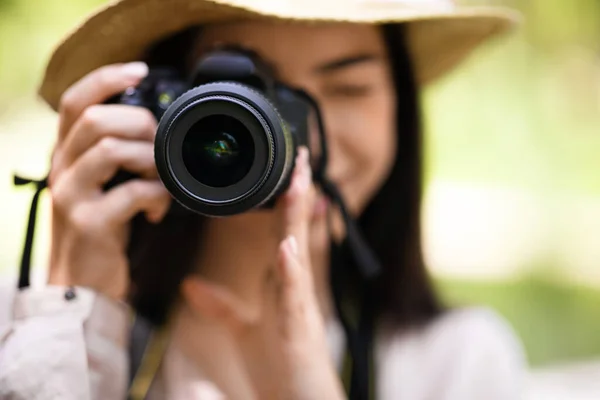 Młoda Azjatka robi zdjęcia w parku z nowoczesnym aparatem fotograficznym, zbliżenie — Zdjęcie stockowe